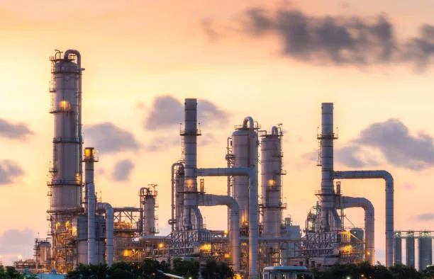 Four tall processing towers and connecting pipes beneath a warm evening sky