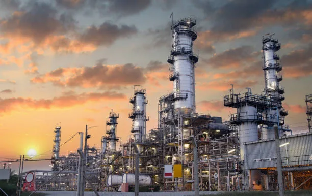 Refinery towers, platforms and pipework against an orange sunset